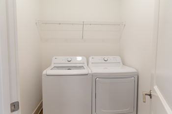 Two white front load washing machines in a small laundry room.